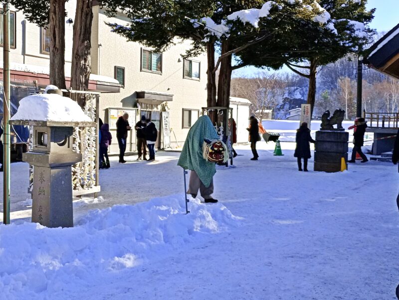 初詣の石山神社の境内に立つ獅子舞