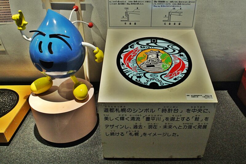 札幌市下水道科学館2階に展示のマンホール蓋と、キャラクターのクリンちゃん